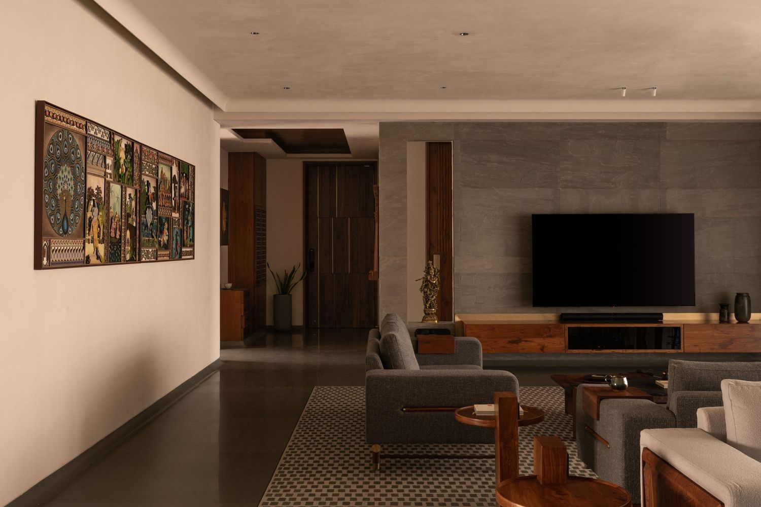 Modern living room with gray sofas, wooden TV console, colorful wall art, and patterned tile flooring.