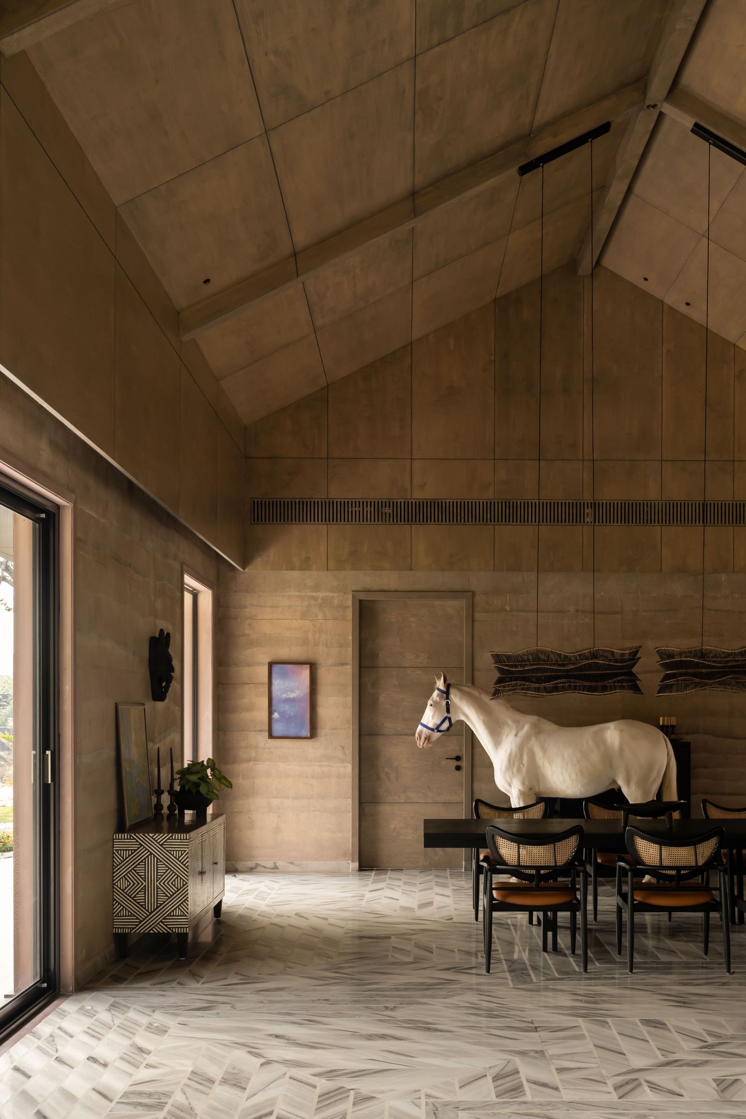 Rustic vaulted stone interior featuring a white horse, dining chairs, and marble floors.