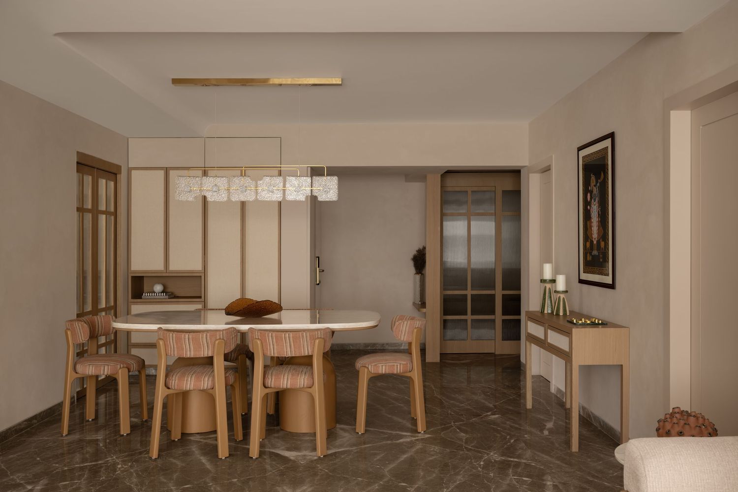 Modern dining room with oval white table, wooden chairs, marble floors, and built-in shelving.