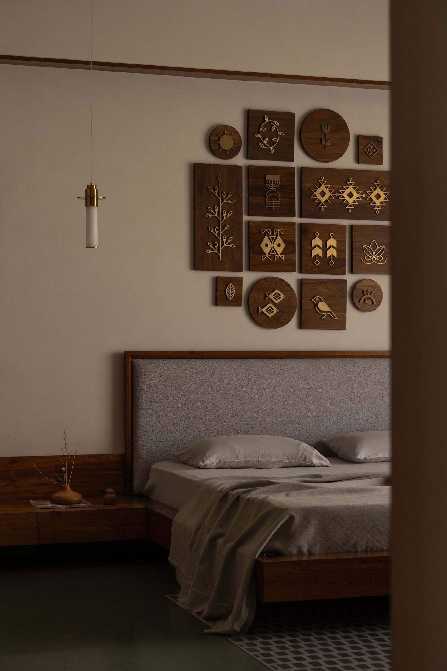 Cozy bedroom with wooden bed frame, gray bedding, and decorative brown wall art panels with gold motifs above headboard.