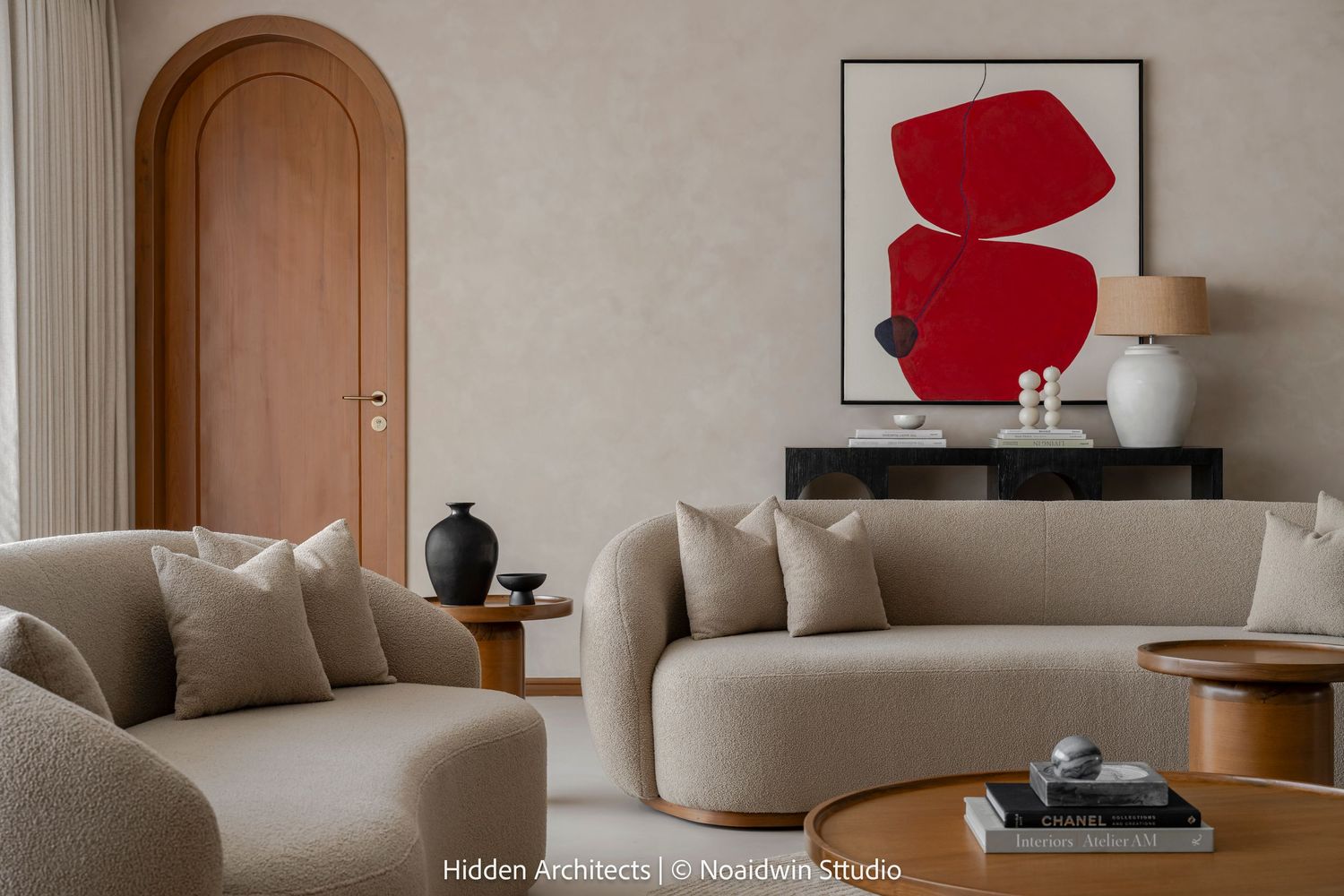 Elegant living room with curved beige sofa, arched door, bold red abstract artwork, and warm lighting.