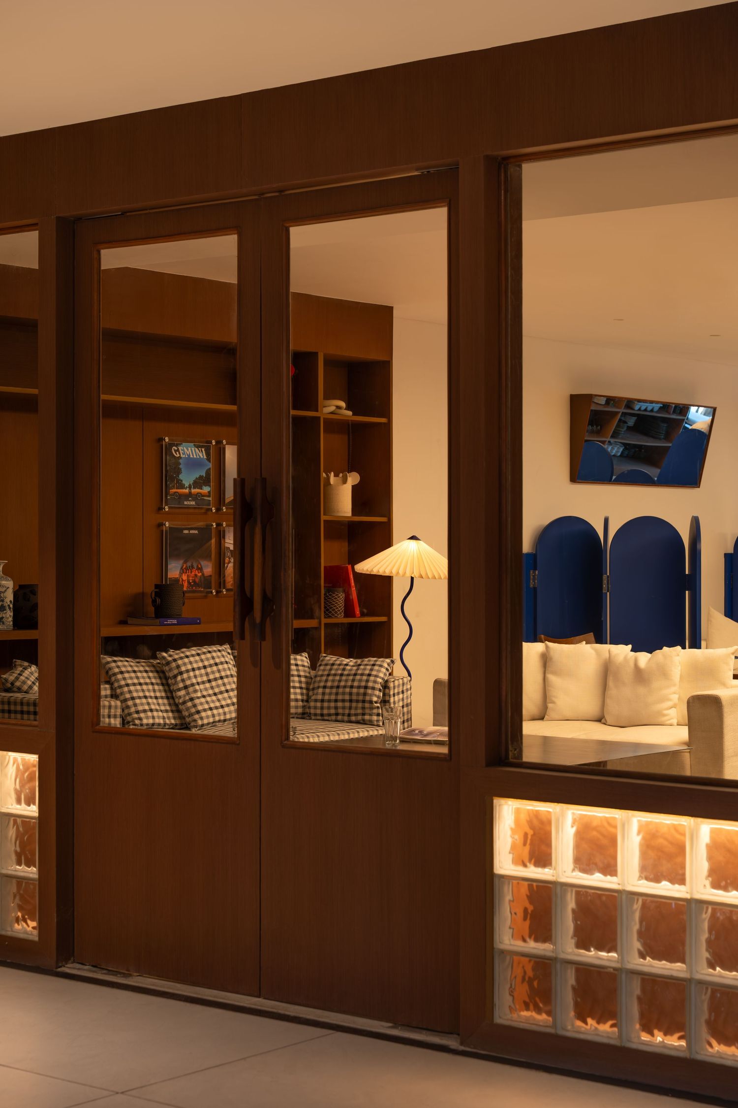 Warm-lit interior storefront with wooden glass doors, illuminated glass block base, and blue decor.