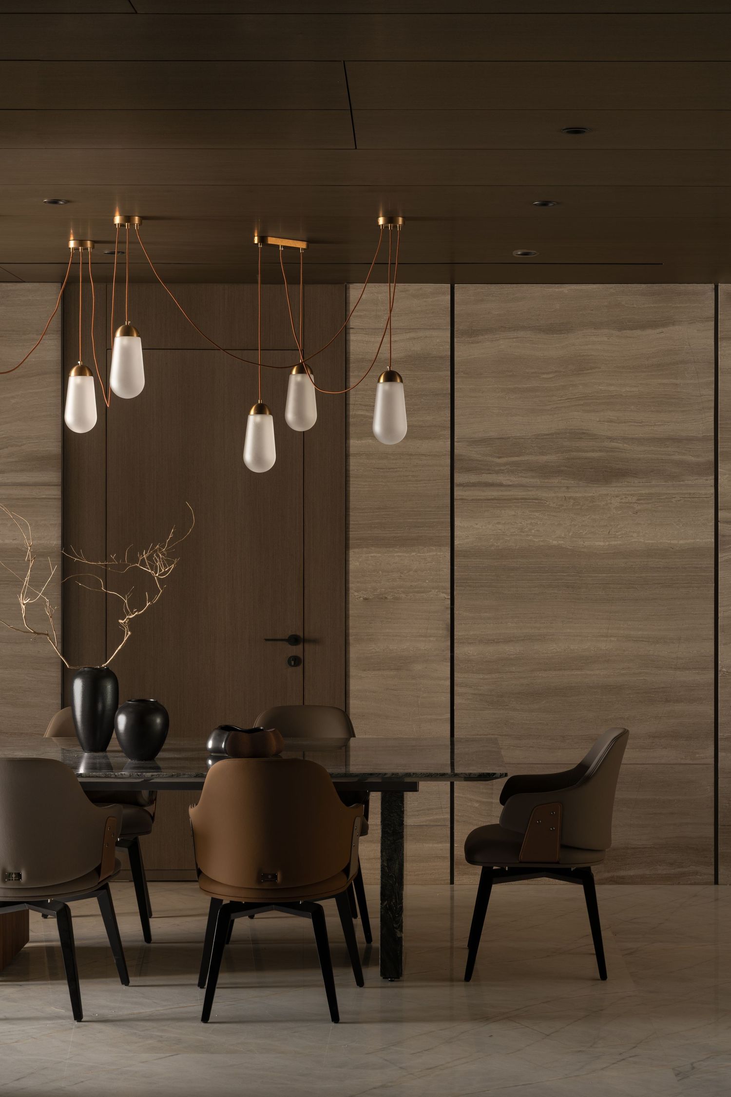 Elegant dining room with pendant lights, dark marble table, brown leather chairs, and wood-paneled walls.