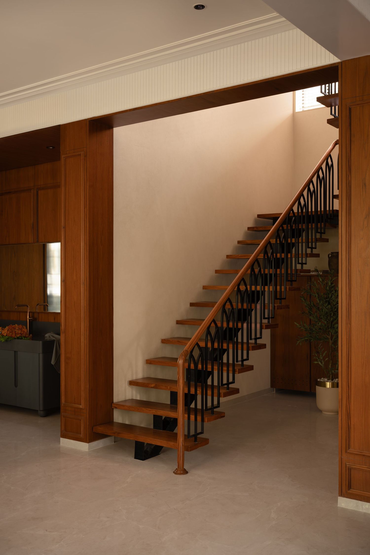 Elegant wooden staircase with black iron balusters and warm oak handrail in a modern home interior.