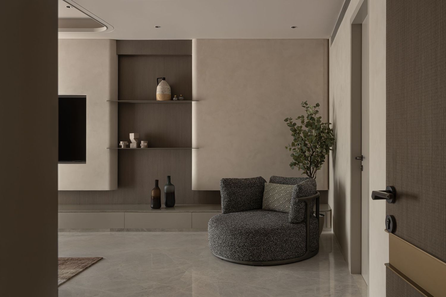 Minimalist living space with built-in shelves, round gray armchair, potted tree, and marble-effect flooring.