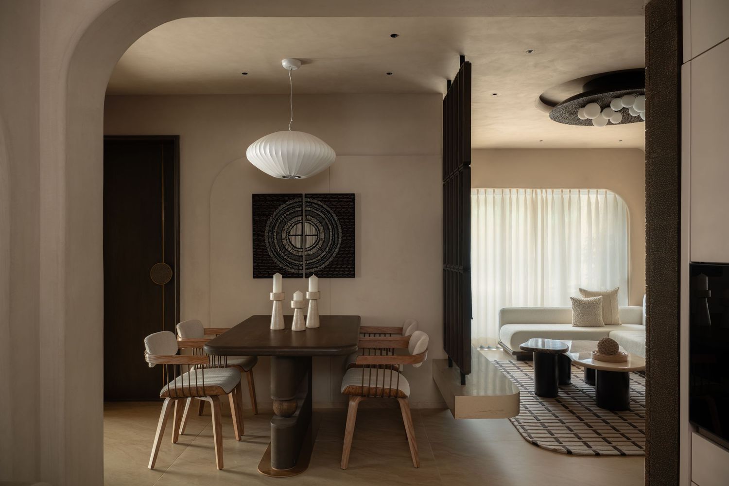 Contemporary dining room with wooden table, pendant light, arched doorway, and neutral earthy tones.