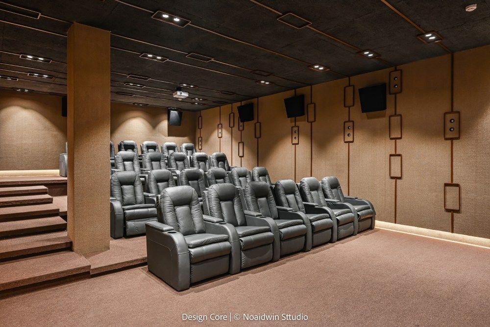 Upscale private home theater with tiered leather recliner seating, warm lighting, and acoustic wall panels.