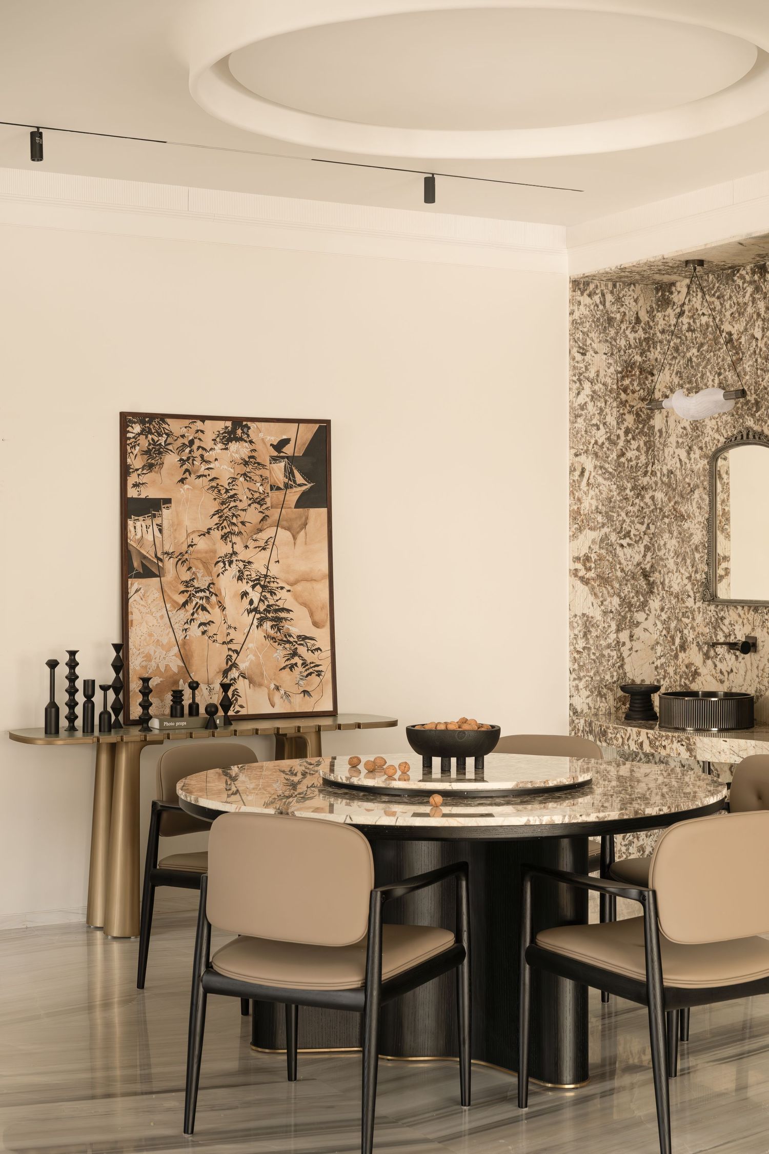 Sophisticated dining room with marble round table, black chairs, floral artwork, and textured stone accent wall.