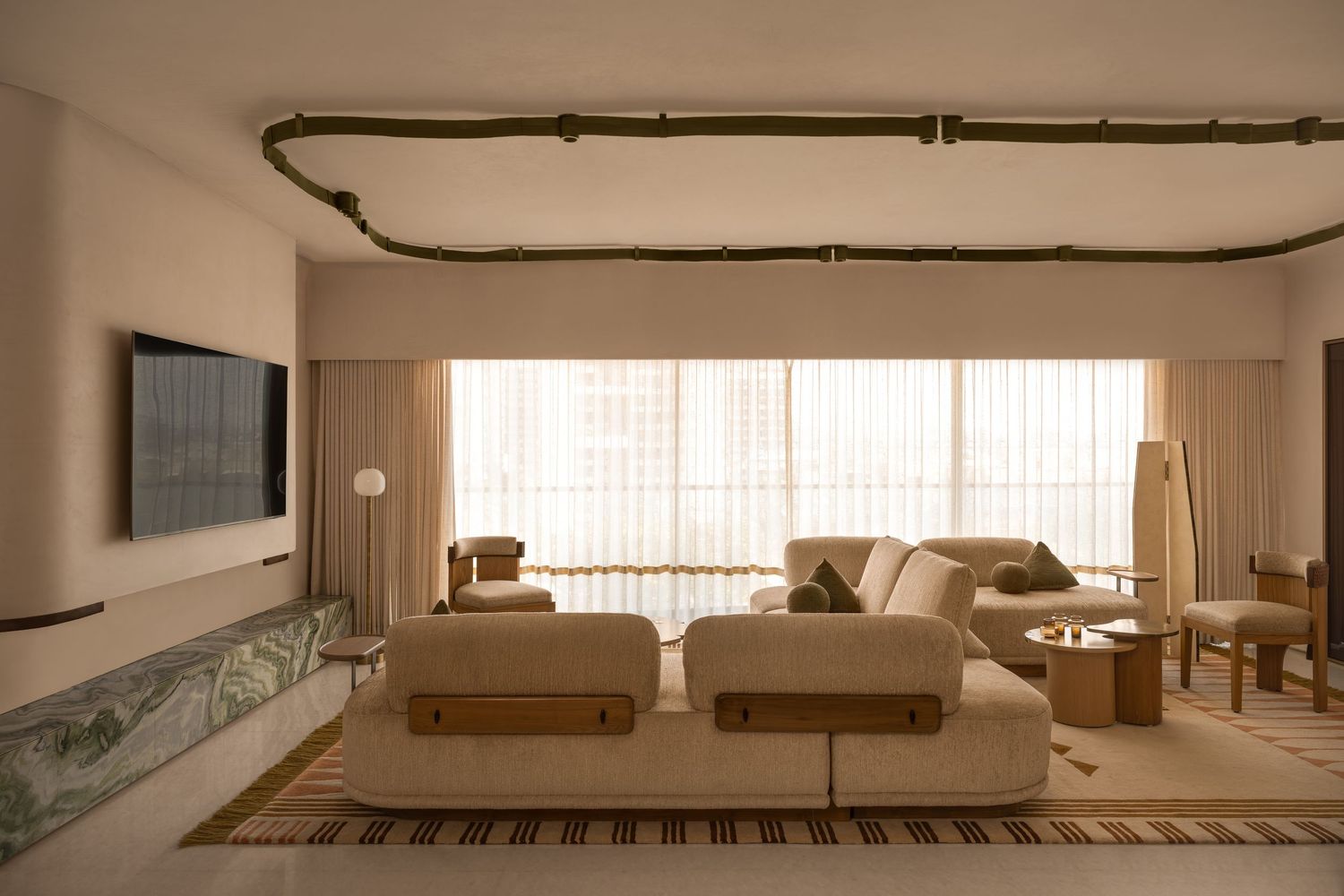 Spacious neutral living room with modular sofa, bamboo ceiling detail, and floor-to-ceiling windows.
