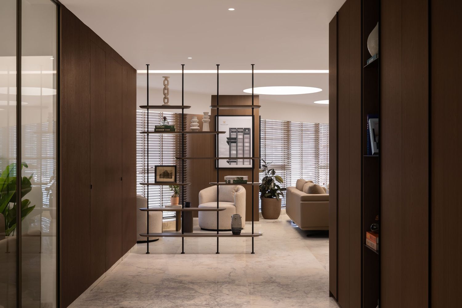 Elegant office corridor with dark wood paneling, open metal shelving divider, and neutral-toned lounge area beyond.