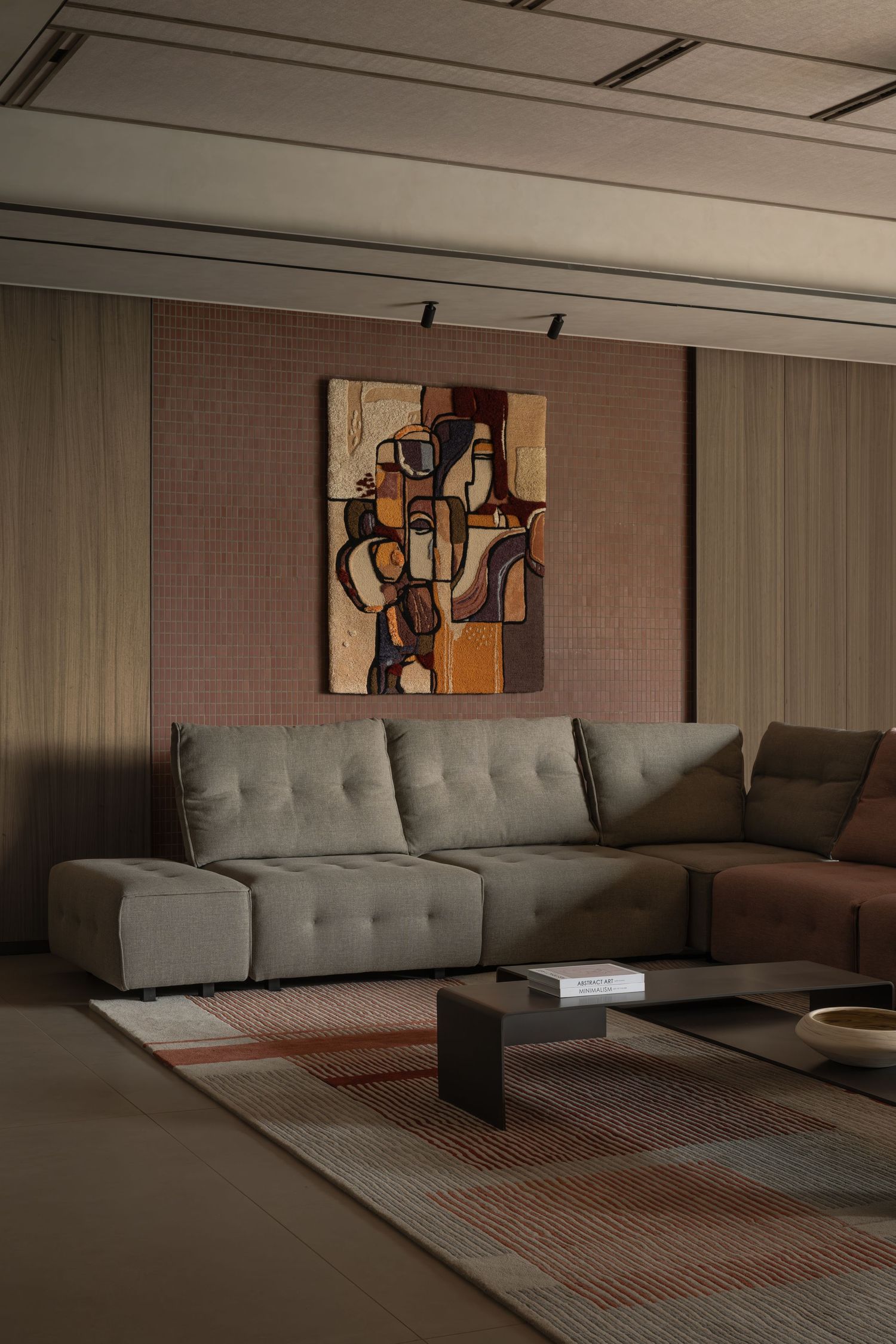Contemporary living room with large gray sectional sofa, cubist artwork, textured wall panels, and striped area rug.