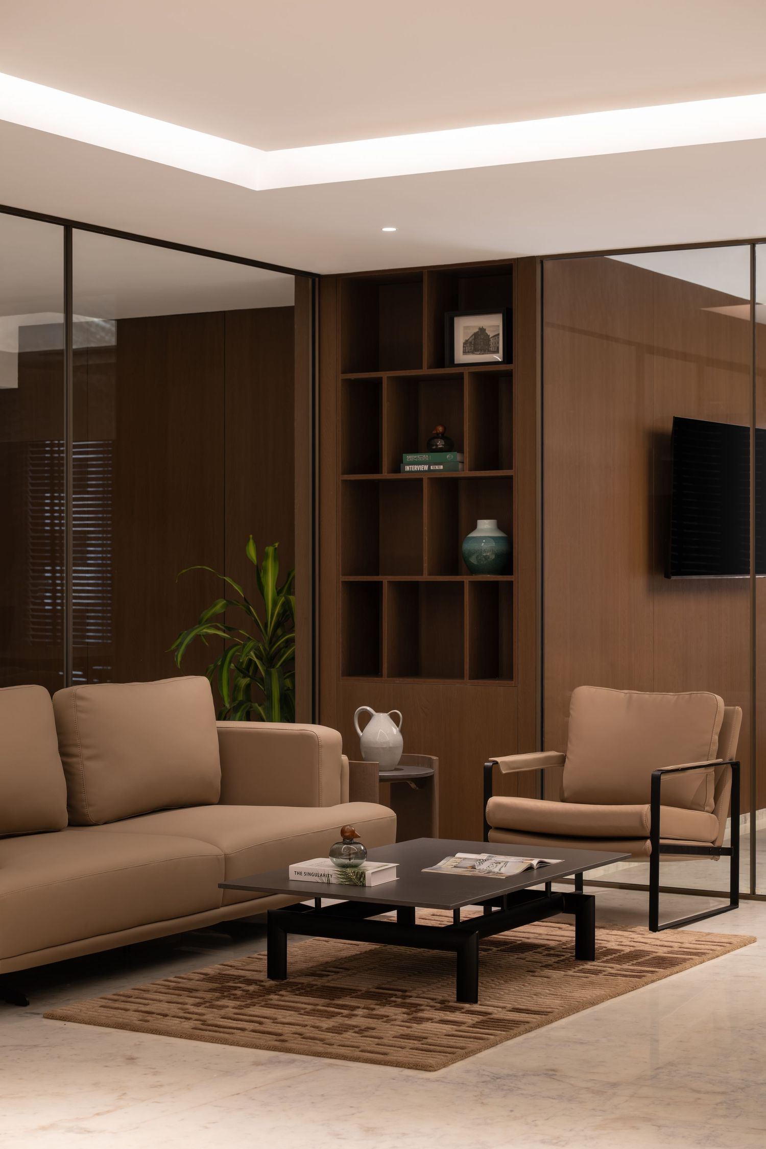 Contemporary lounge with beige sofa, armchair, black coffee table, built-in wood shelving, and wall-mounted TV.