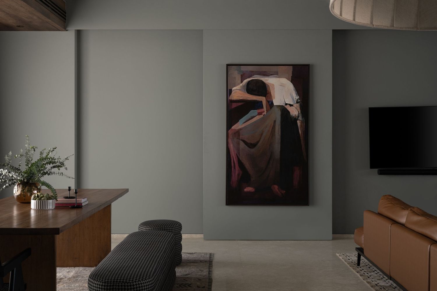 Modern living room with large figurative artwork, wooden console, leather sofa, and wall-mounted TV.