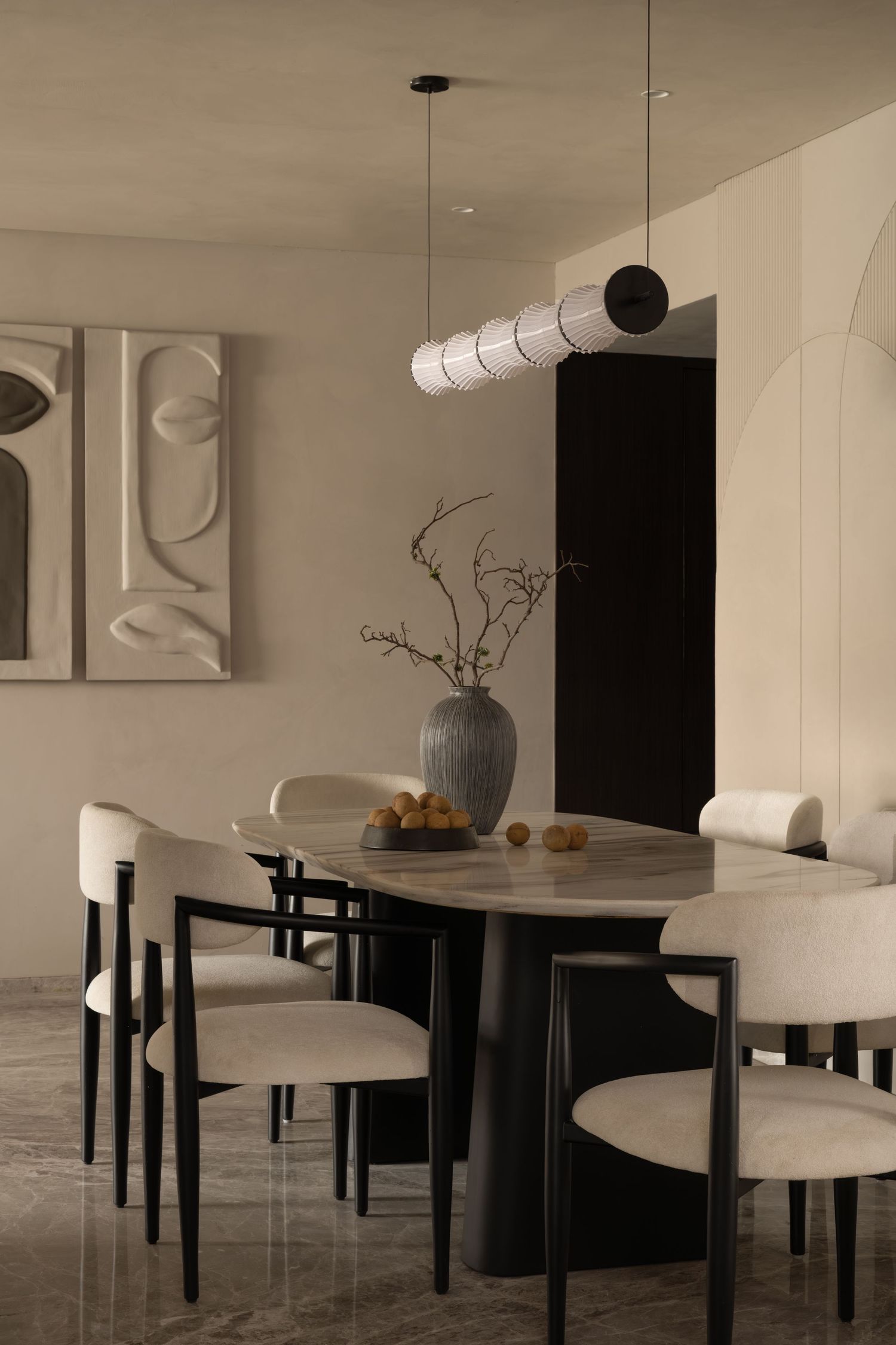 Elegant dining room with oval table, cream upholstered chairs, pendant light, and sculptural wall art.