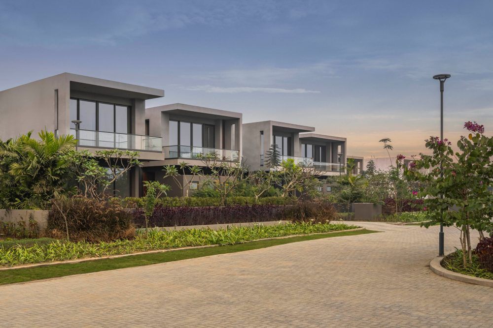 Modern residential villas with landscaped gardens and paved pathway photographed at twilight.
