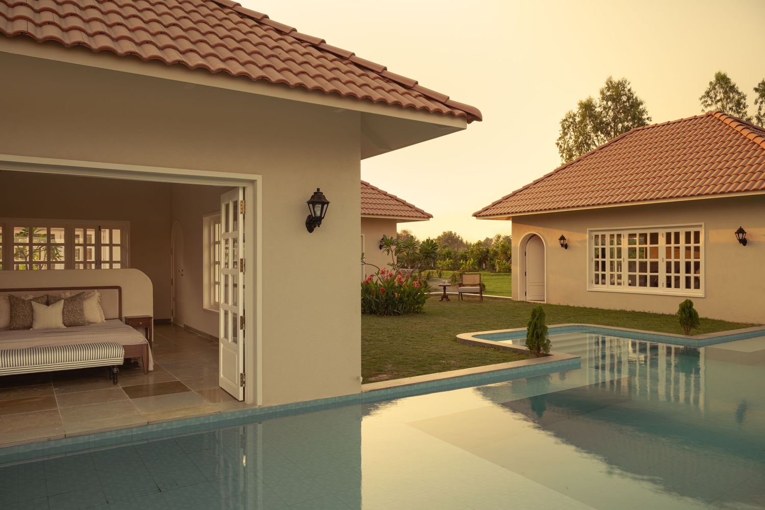 Stunning villa at dusk featuring infinity pool, terracotta roof tiles, and open living space with warm lighting.