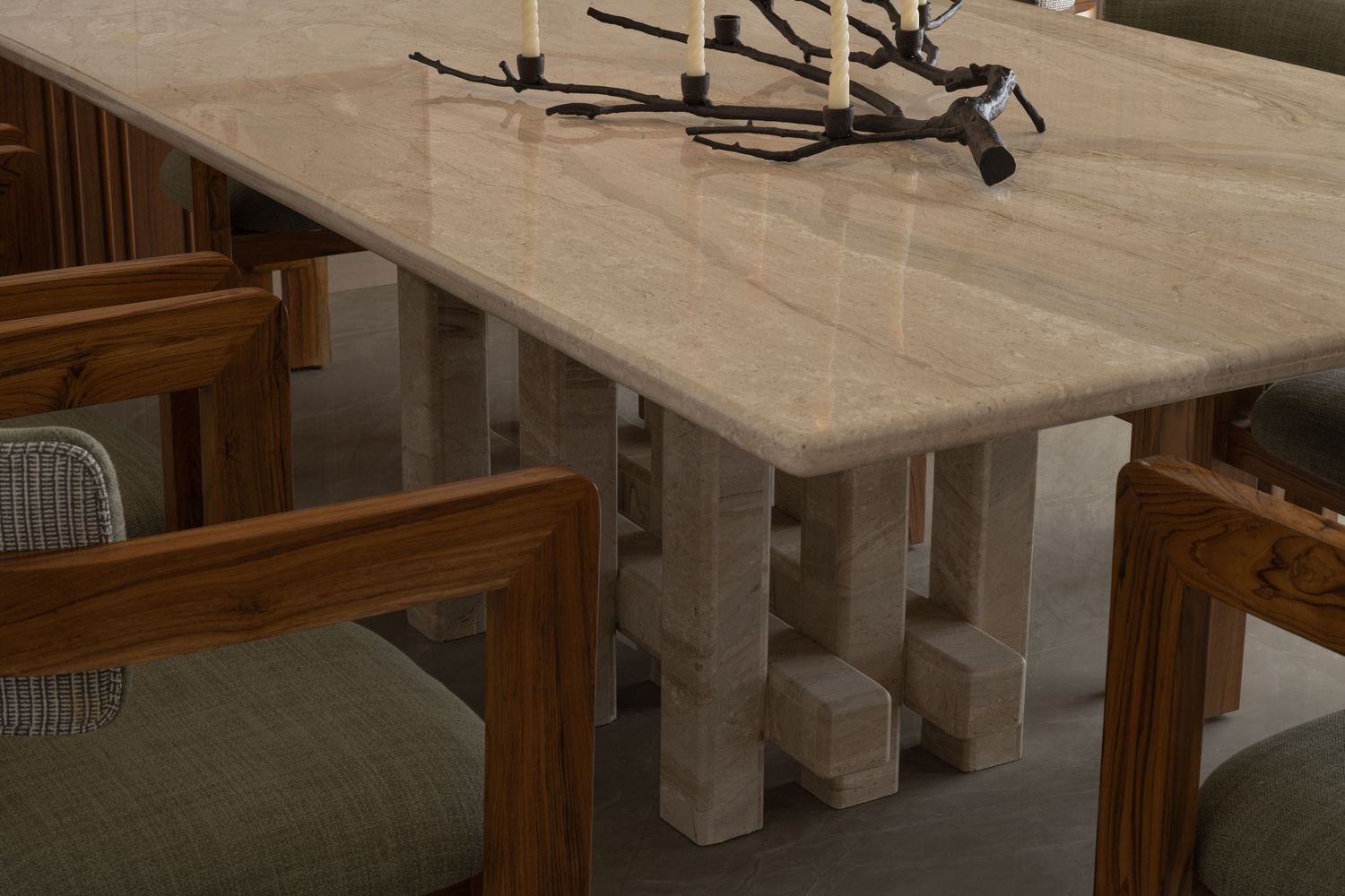 Minimalist marble dining table with sculptural base and wooden chairs in warm interior.