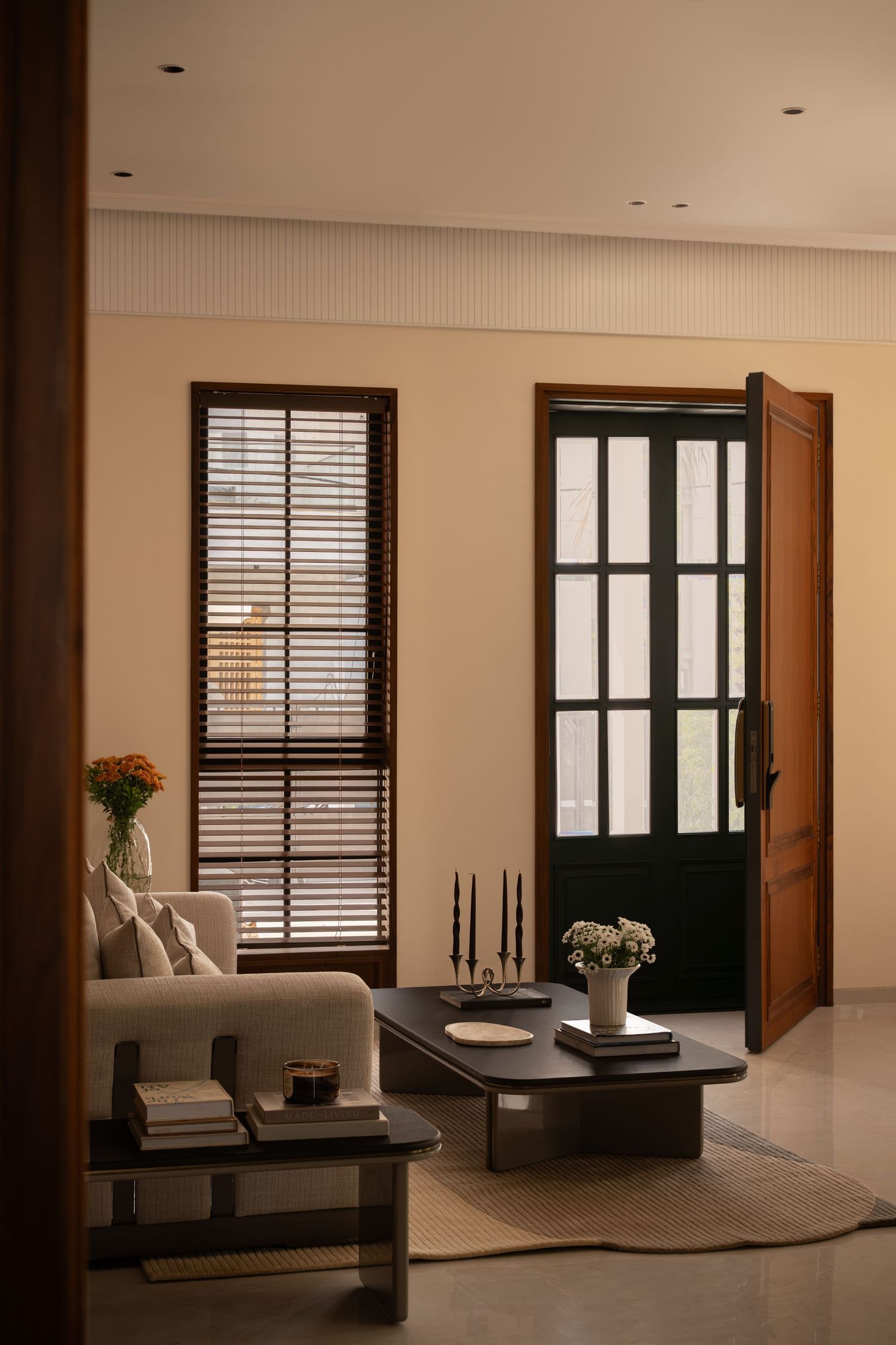 Warm interior with dark wood shutters, French doors, black coffee table, and candle arrangement.