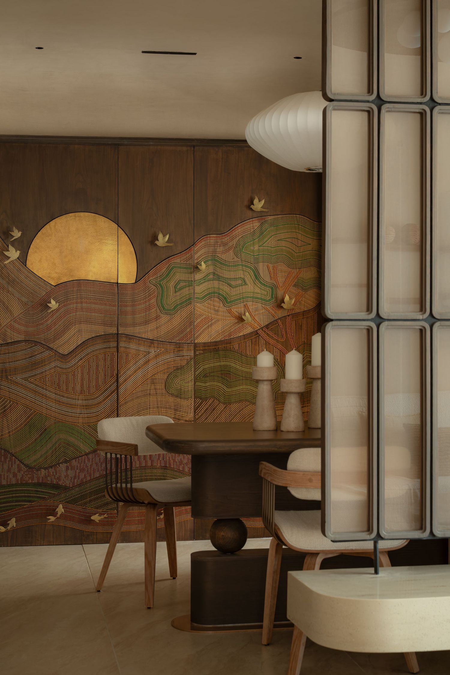 Artistic dining area featuring an ornate wood mural with golden sun motif, round table, and rattan chairs.