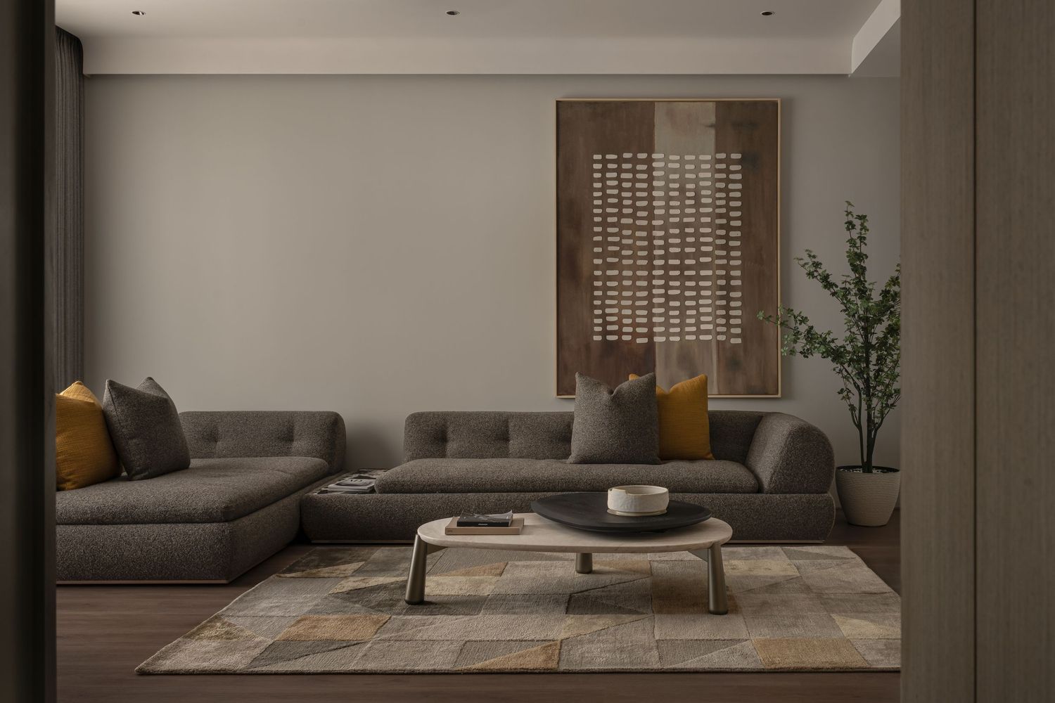 Modern living room with gray sectional sofa, mustard pillows, round coffee table, and decorative wall art.