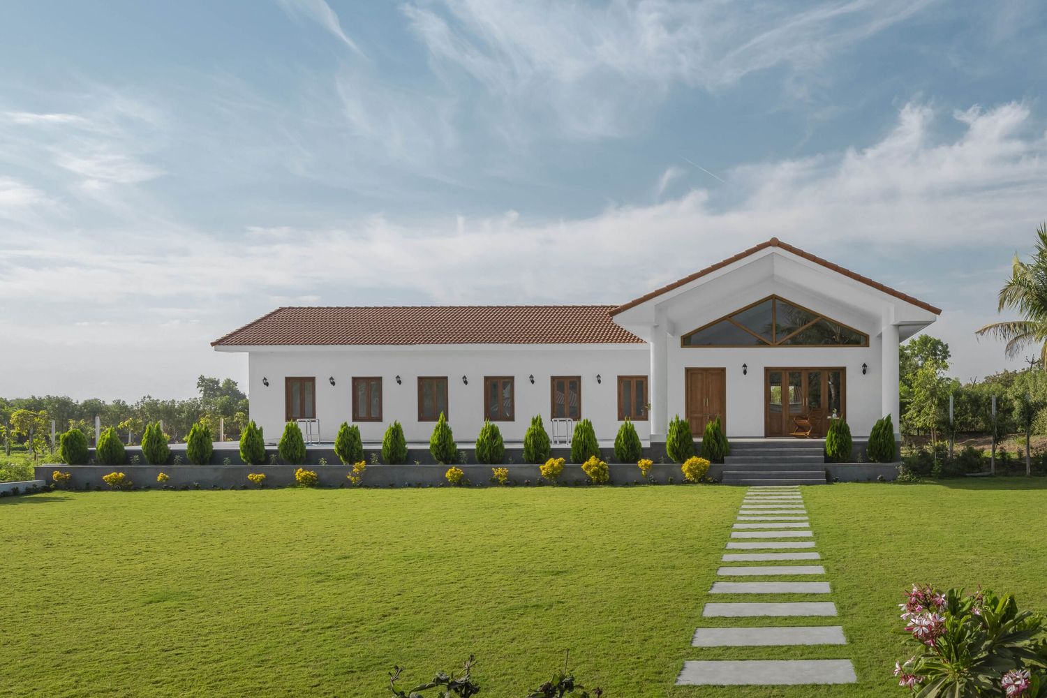 White single-story country home with terracotta roof, stepping stone pathway, and lush green lawn.