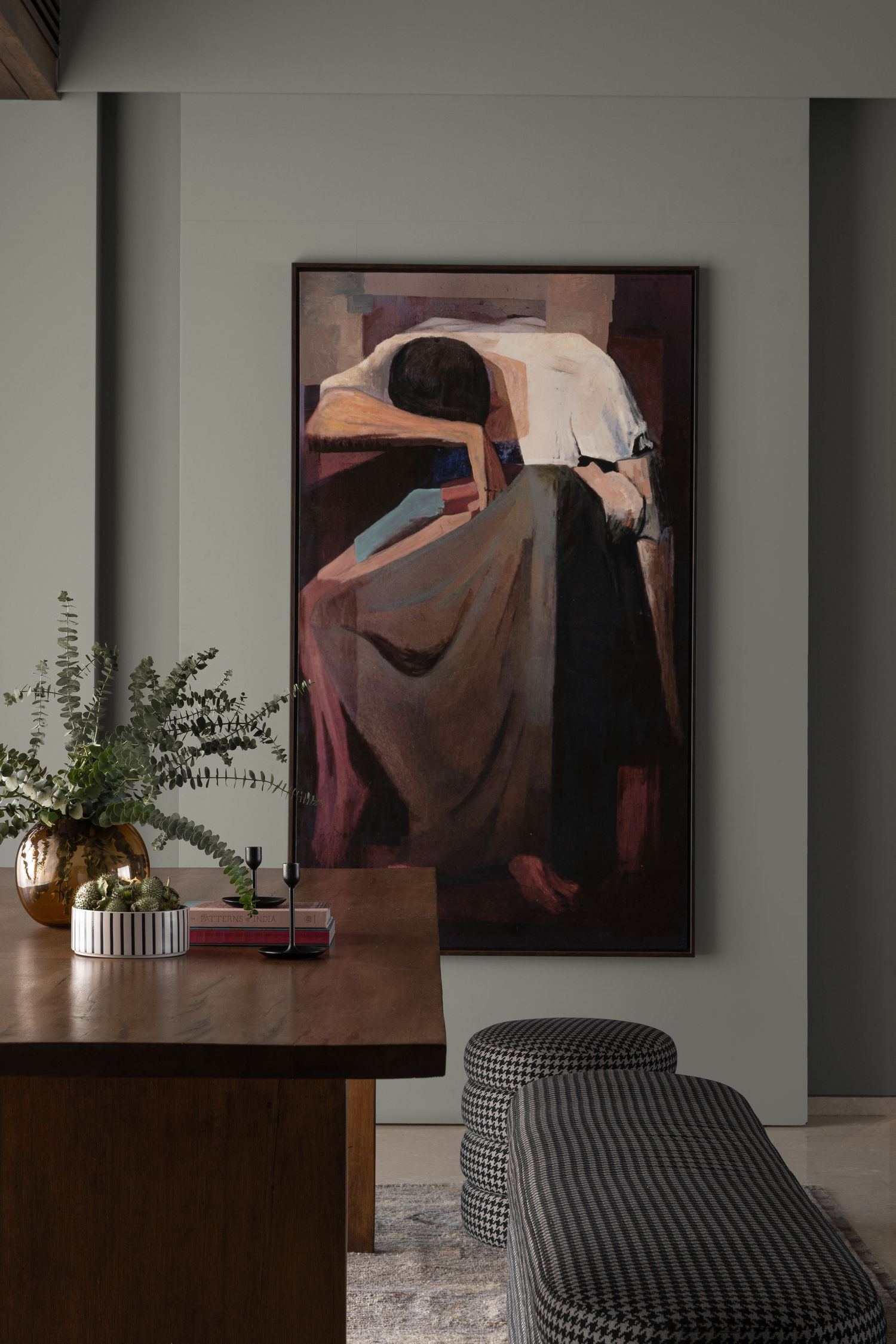 Elegant dining area featuring large figurative wall art, wooden table, and houndstooth upholstered stools.