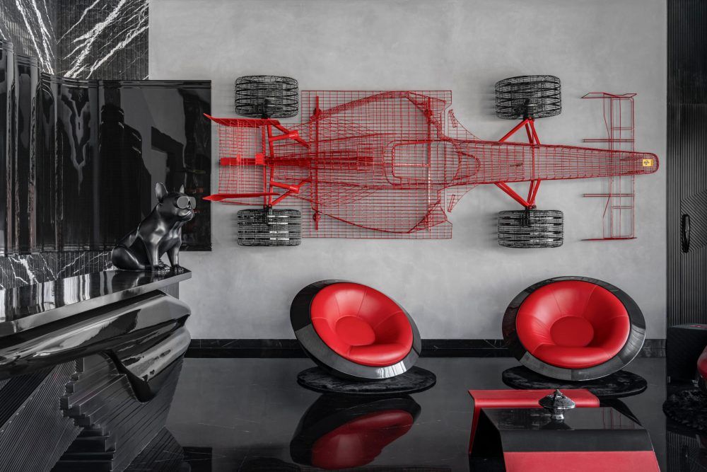 Luxury lounge with red wire Formula 1 car wall art, red pod chairs, and black reflective floors.