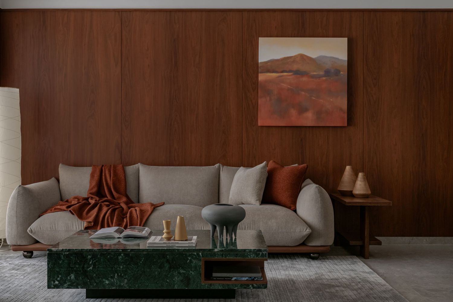 Contemporary living room with gray sofa, terracotta cushions, green marble coffee table, and landscape painting.