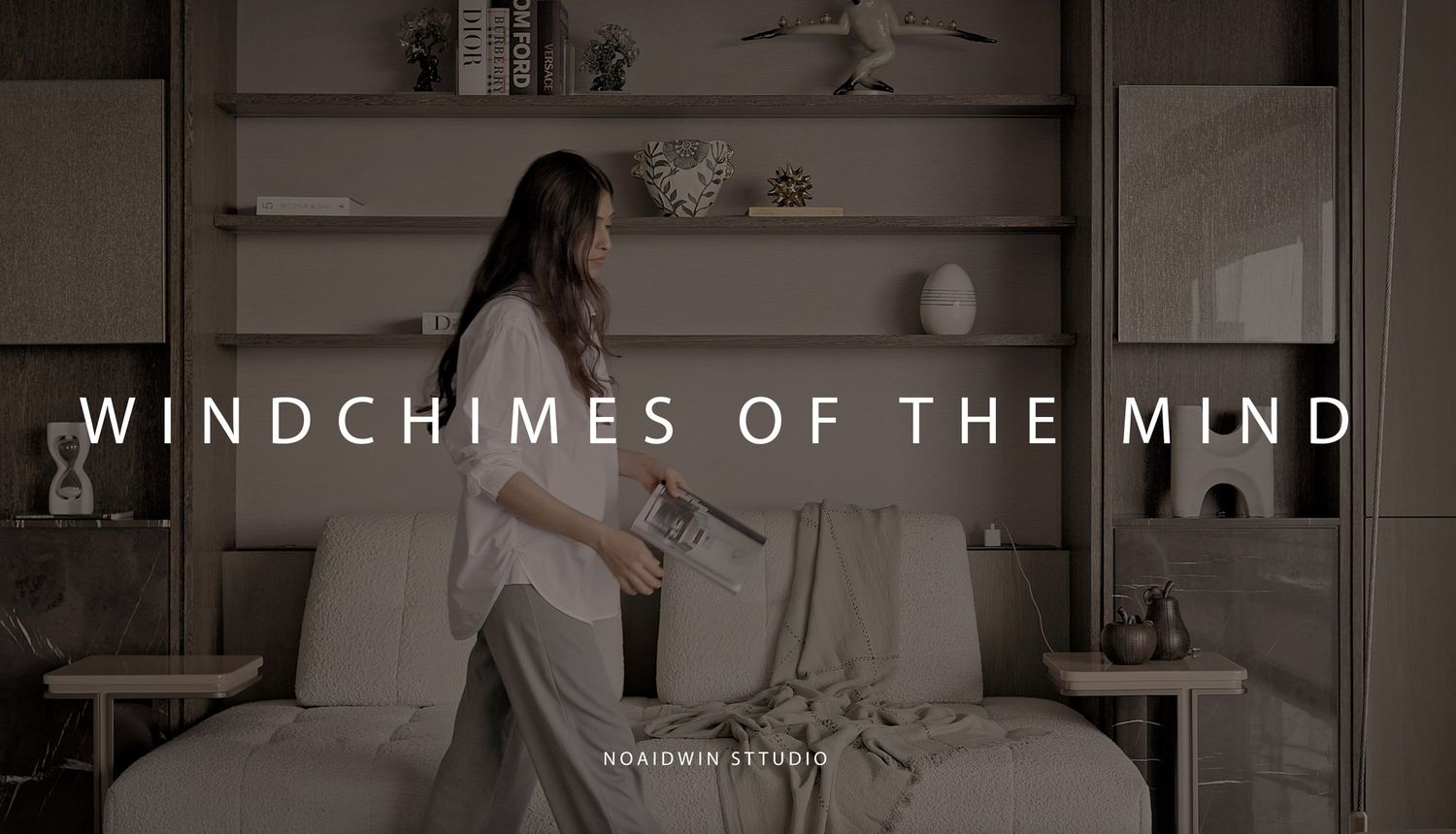 A woman in a white dress arranges items on a modern sofa in a minimalist room, featured in Windchimes of the Mind.