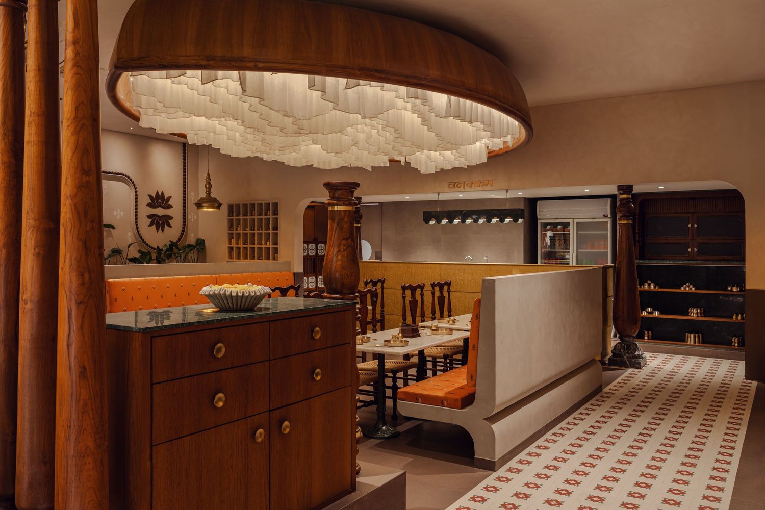 Stylish restaurant bar area featuring a large cloud-like chandelier, warm wood tones, and patterned tile flooring.