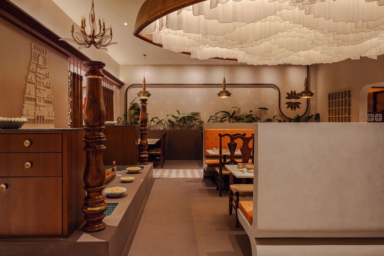 Warm Indian restaurant interior with wooden furniture, patterned floors, and decorative ceiling installation.