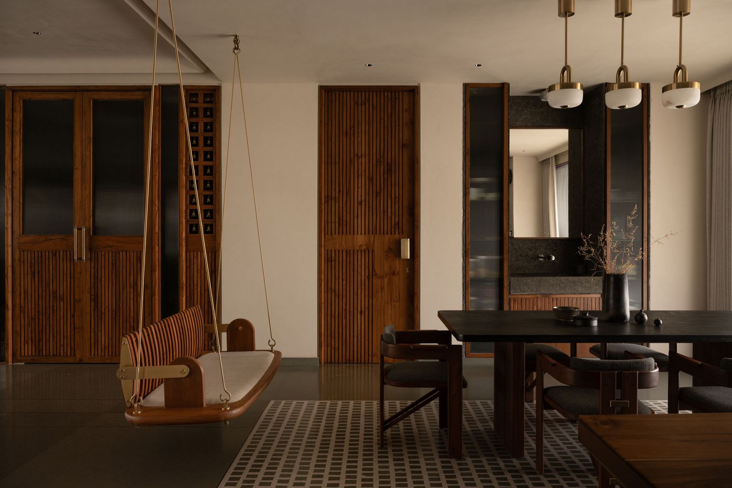 Stylish dining area with wooden swing, dark table, pendant lights, mirror, and geometric patterned floor tiles.