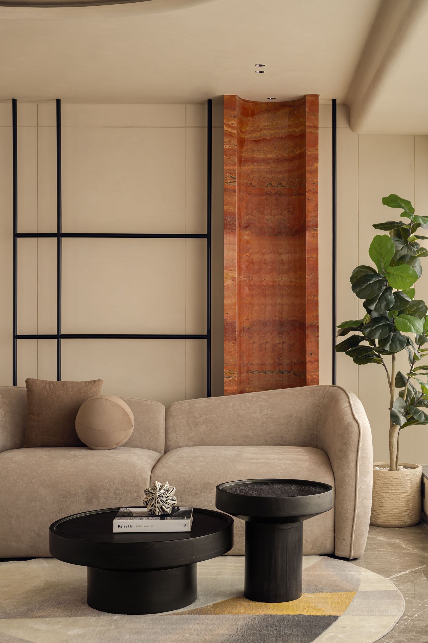 Modern living room with beige curved sofa, black round coffee tables, wood art panel, and fiddle leaf fig.