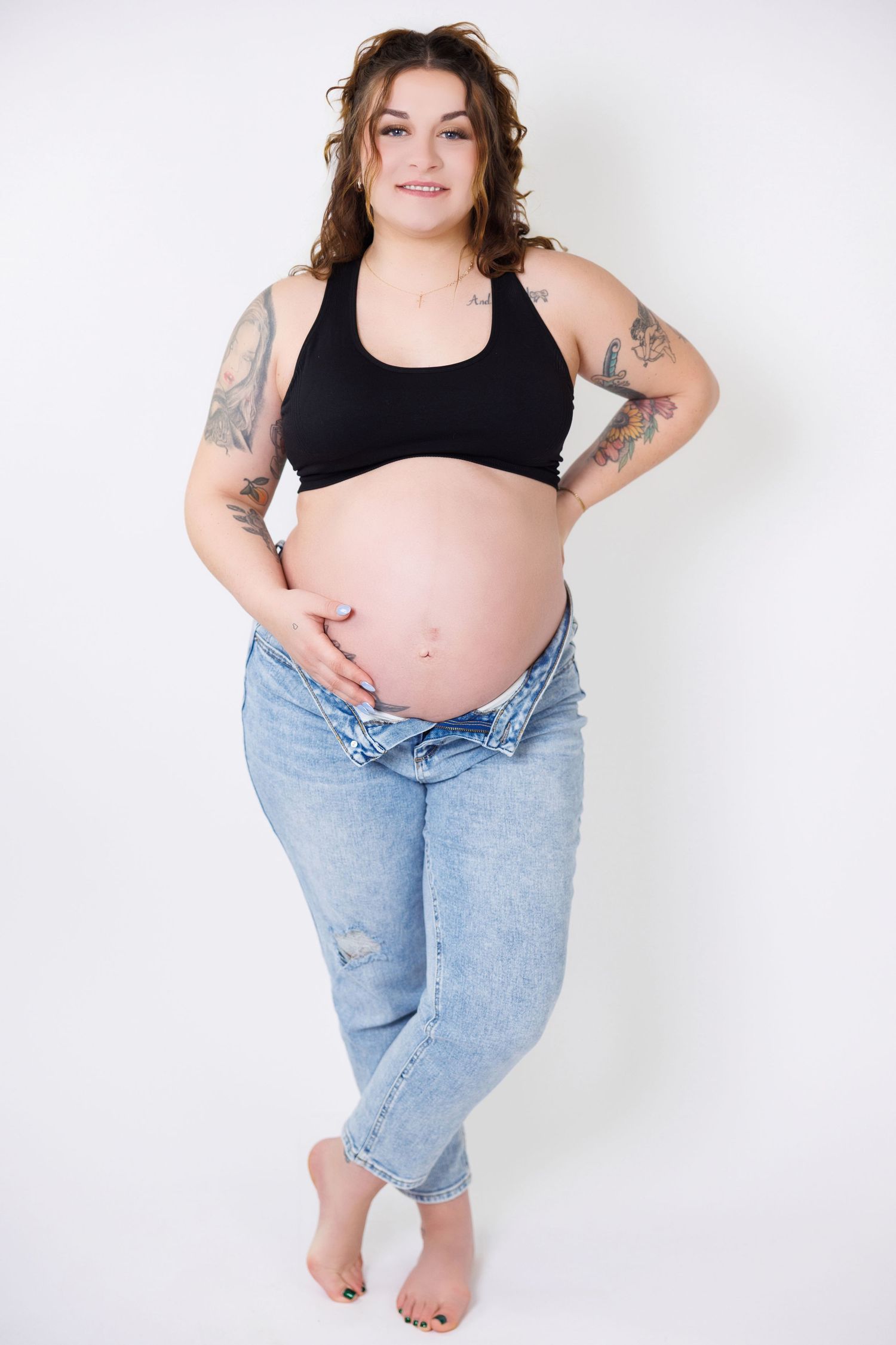A series of maternity photos showing a pregnant woman in a black tank top and jeans against a white background.