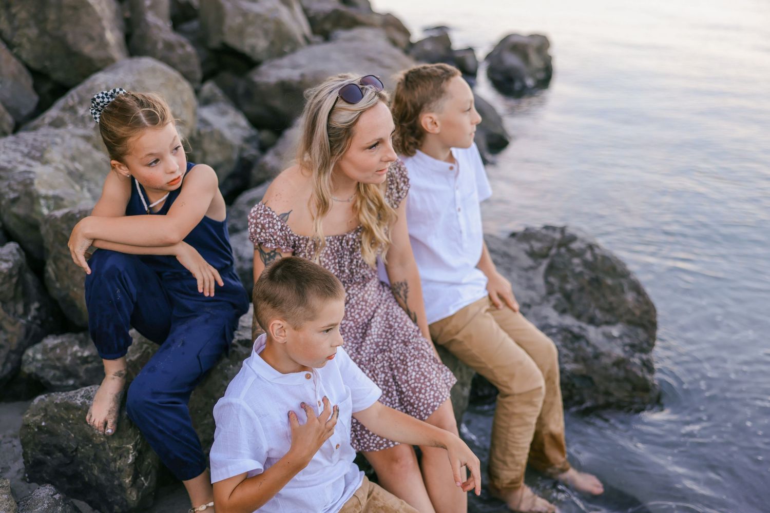 Casual beach portraits of family relaxing on coastal rocks.