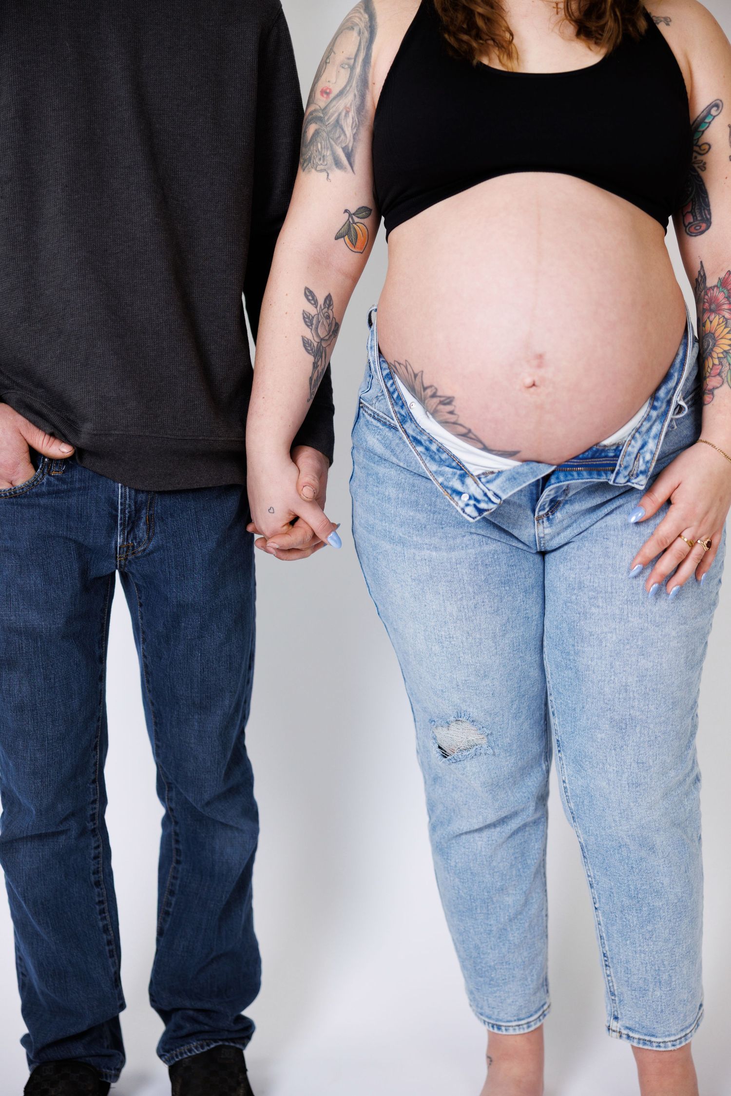 A side-by-side comparison showing the progression of a pregnancy belly growing over time in denim jeans.