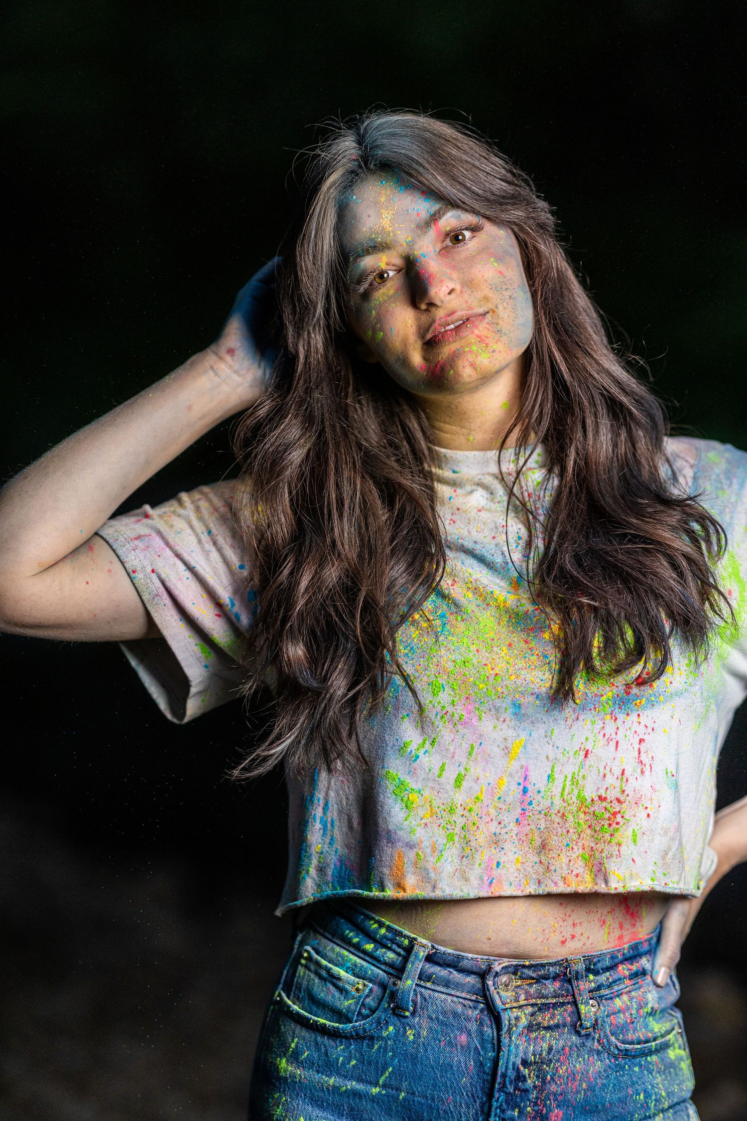 A person in a paint-splattered white t-shirt and jeans poses dynamically against a dark background.