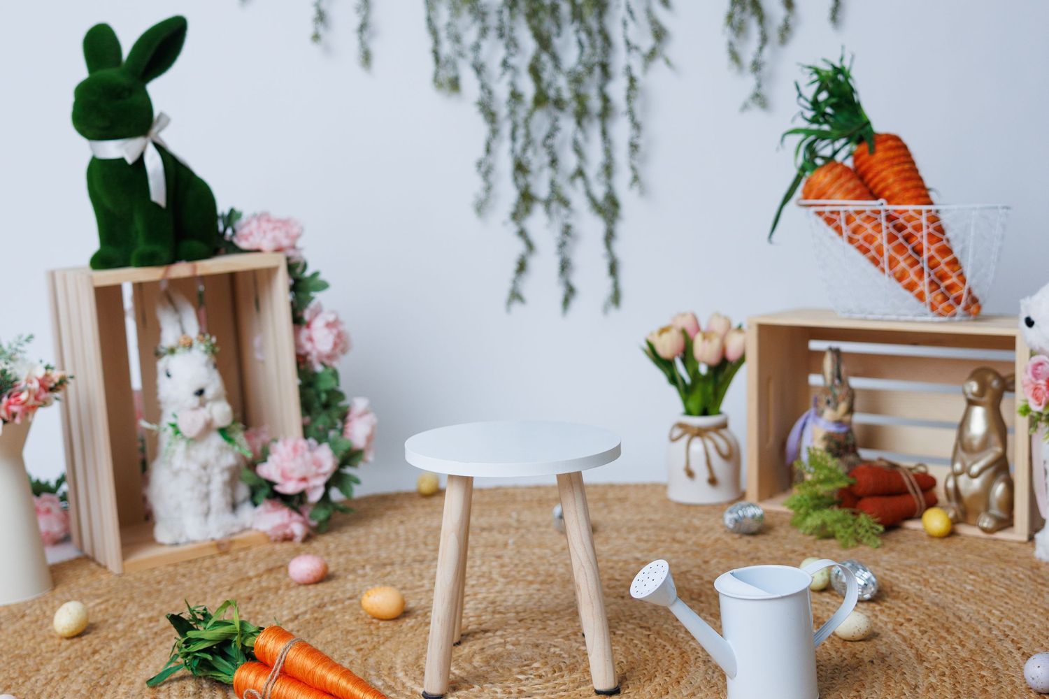 A minimalist table setting with white vases, plants and orange accents against a light neutral backdrop.