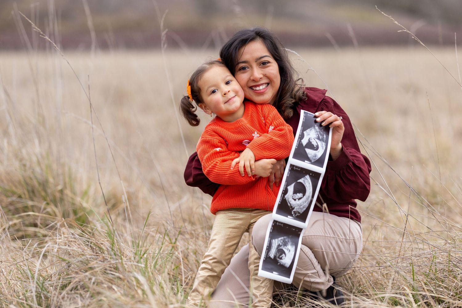 Candid family photos in a field showing sonogram prints and joyful expressions.
