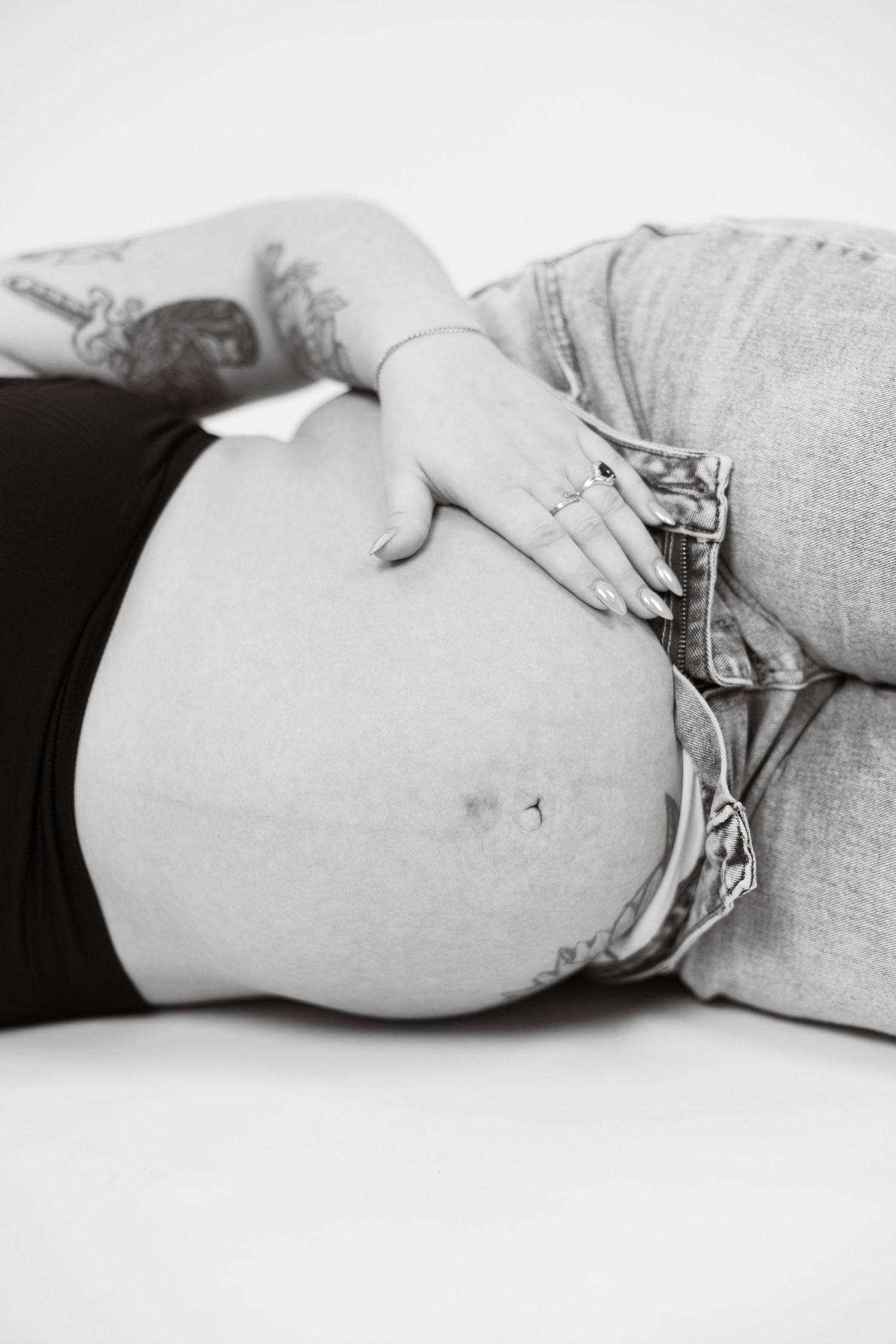 Black and white artistic maternity photo series showing pregnant belly in different angles with gentle hand placement.