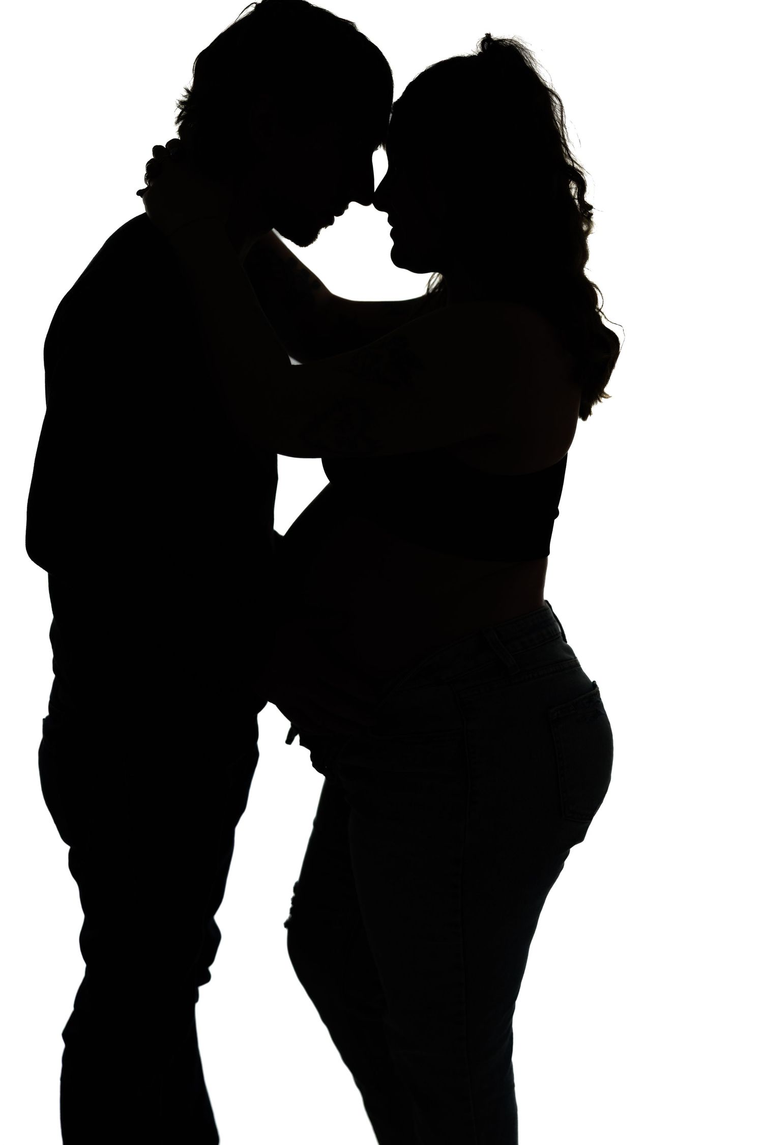 A romantic silhouette shows a couple in an intimate embrace with their faces close together against a white background.