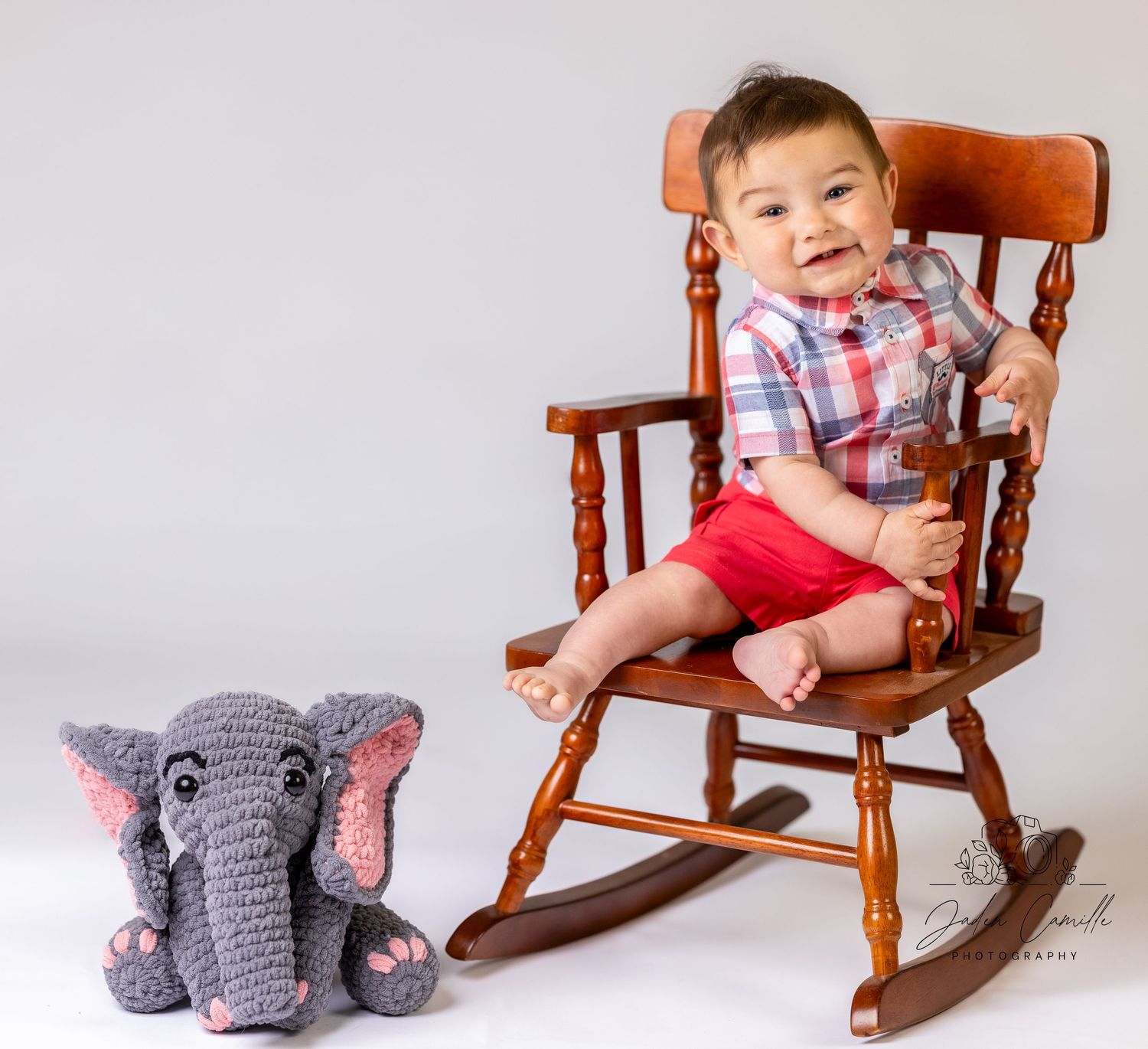 A baby sits in a wooden rocking chair next to a knitted gray elephant toy in a progression of four photos.