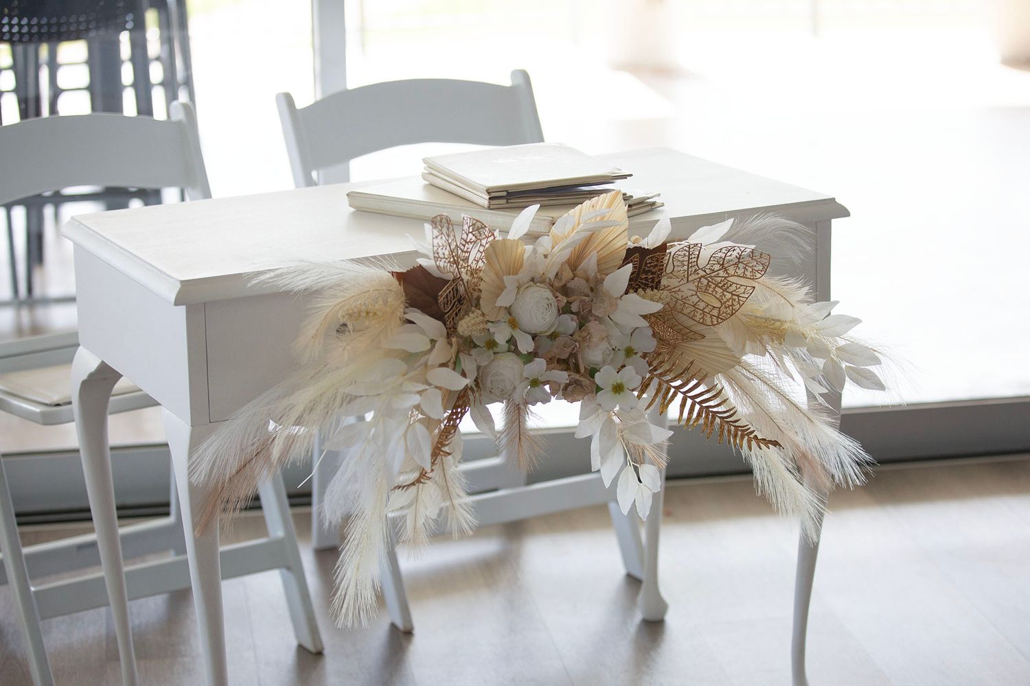 White and gold wedding reception decor with feather and floral arrangements.