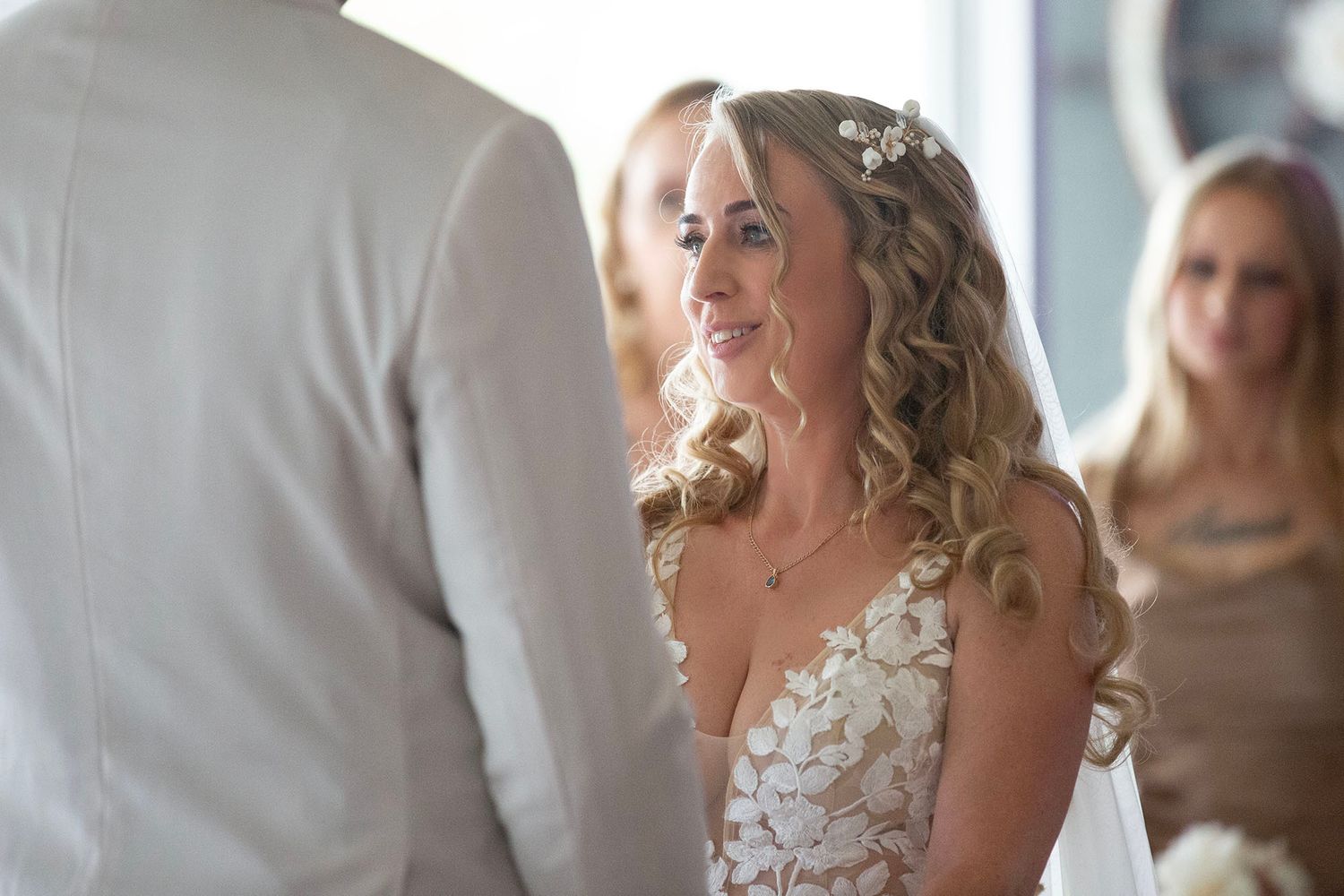 Side profile view of bride in white floral dress during wedding preparations.