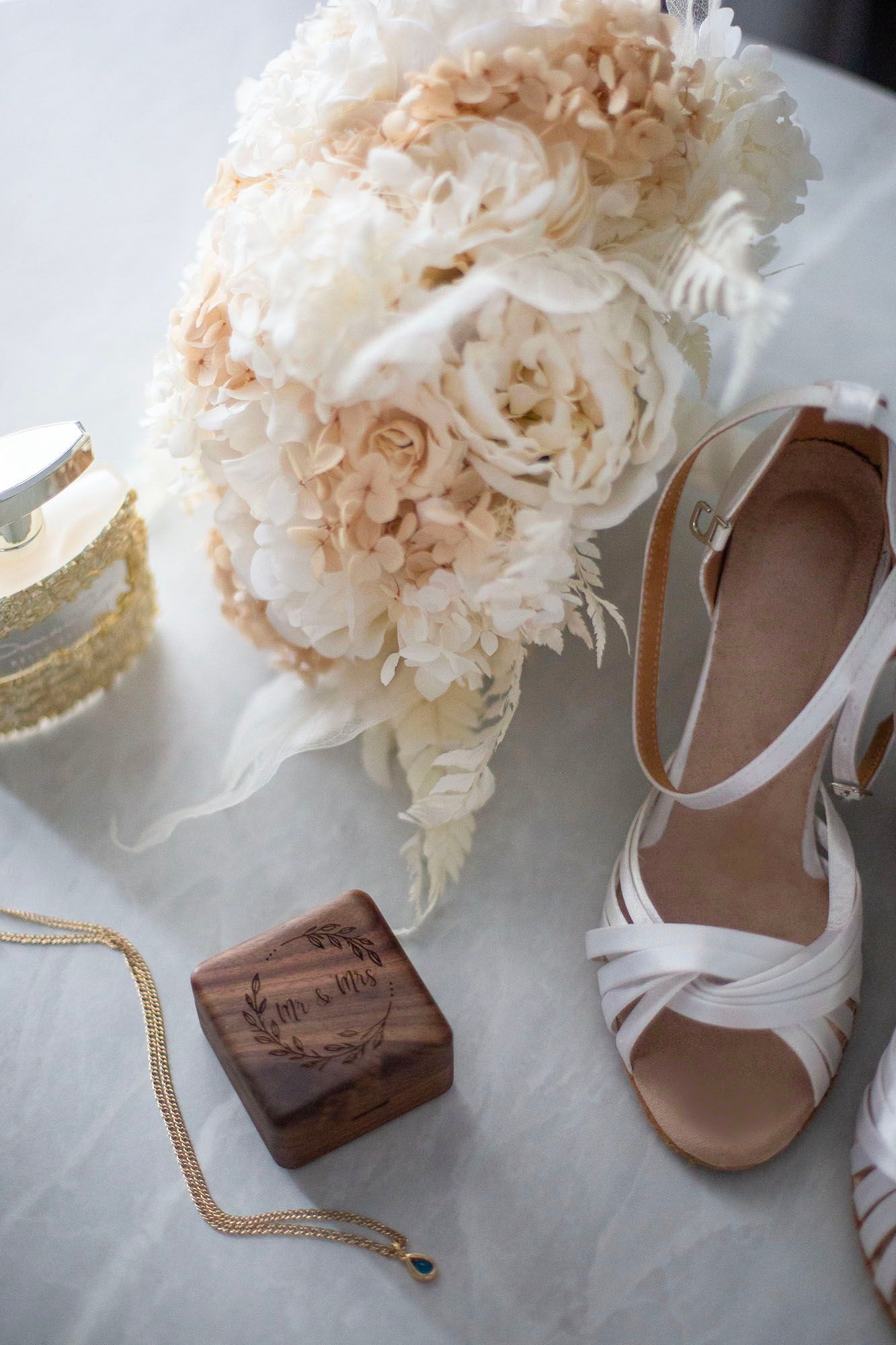 Wedding accessories featuring white floral bouquet and elegant sandals with gold accents.