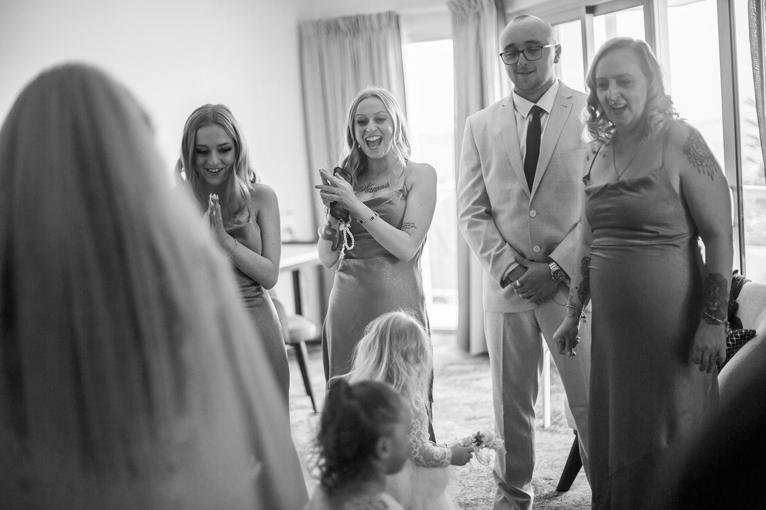 Wedding party sharing joyful expressions during a bright indoor celebration.