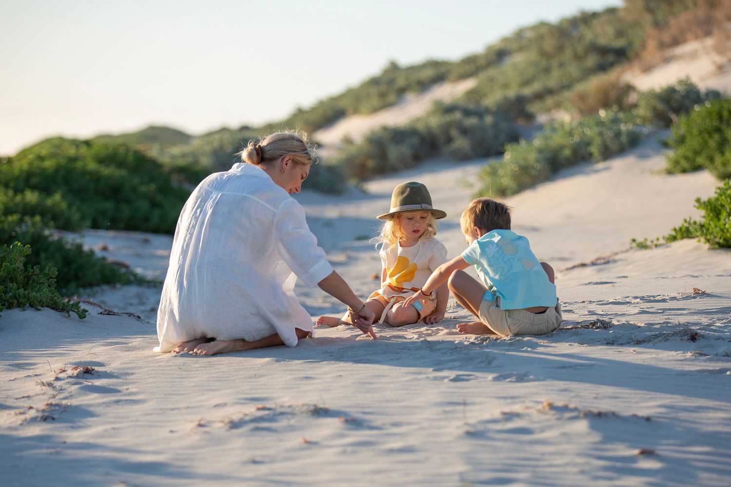 Group relaxing together on a scenic coastal beach with dunes during golden hour.