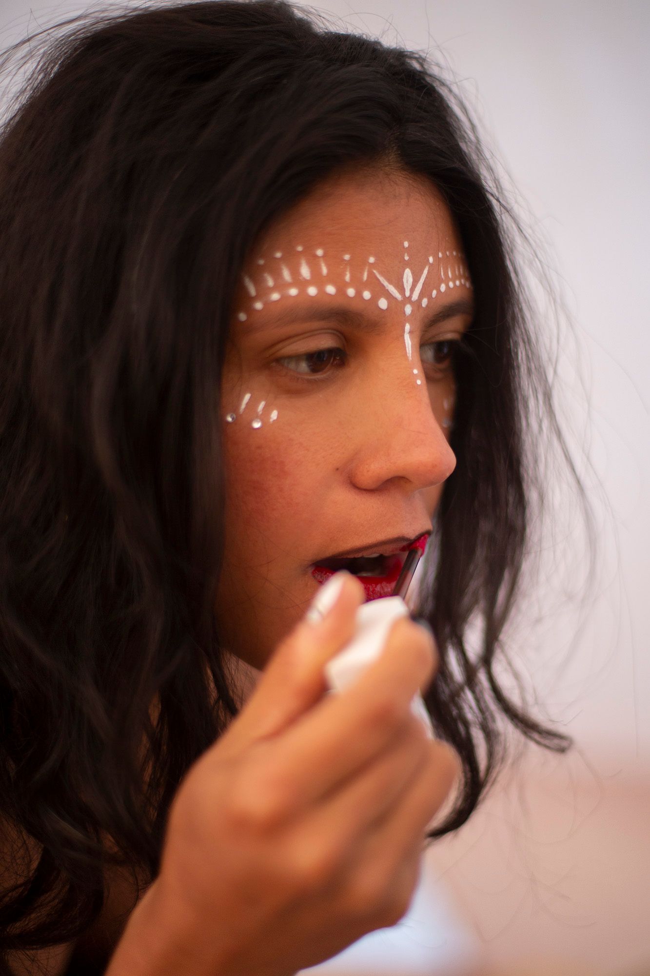 White face paint designs being carefully applied around eyes and features.