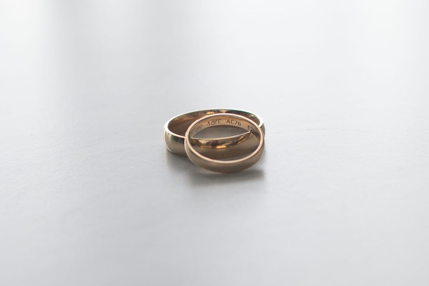Gold wedding rings placed on a white surface with soft lighting.