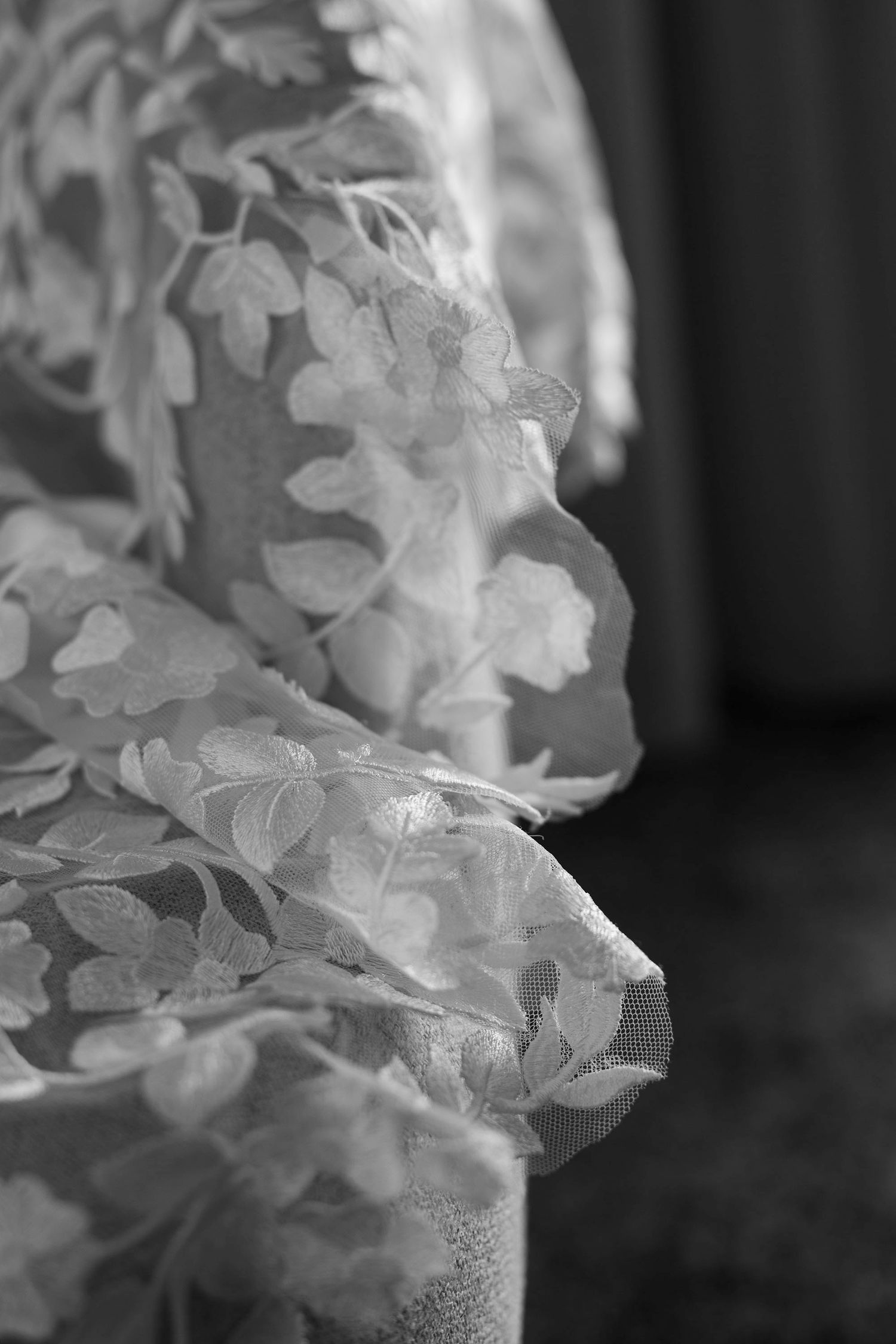 Close-up of intricate white lace fabric details in monochrome.
